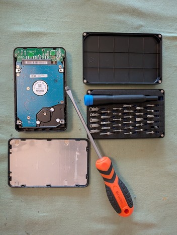 The opened hard drive, it's enclosure and the flathead screw driver